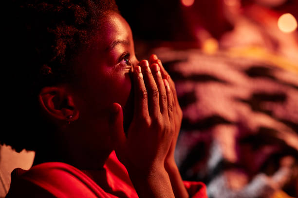 side view of shocked girl covering mouth in movie theater